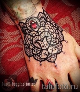 Фото тату: изящное кружево с красным акцентом на руке, выполненное в технике blackwork. Детализированный рисунок татуировки для вдохновения.