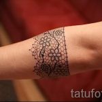 Фото тату: кружево с цветами на запястье. Детализированный рисунок татуировки в черном цвете.