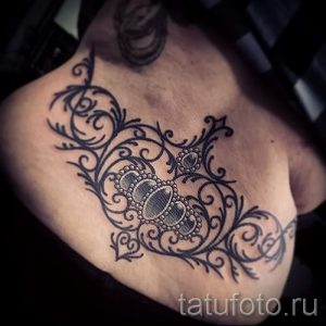 Фото тату: кружевная татуировка на плече, выполненная в черных тонах. Рисунок охватывает верхнюю часть плеча и часть груди, создавая эффект украшения.