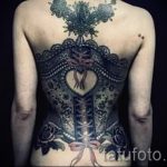 Фото татуировки, имитирующей корсет с кружевом и лентами на спине. Оригинальный и смелый выбор для тех, кто любит необычные рисунки.