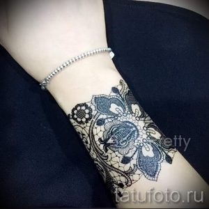 Фото тату: черно-белая татуировка в виде кружевного узора, покрывающего женскую руку. Детализированный рисунок с акцентом на текстуру и тени.