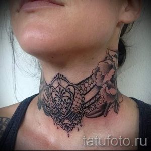 Фото тату: изящное черное кружево и розовая роза, расположенные на шее девушки. Детализированный рисунок татуировки.