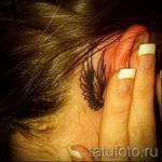 Фото татуировки крыла за ухом, выполненной в черном цвете в стиле графика. Тонкие линии и детализированная проработка создают изящный рисунок.