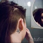 Фото тату маленькой ласточки на затылке. Черно-белый силуэт птицы, расположенный у основания шеи.