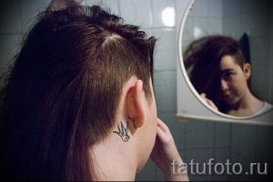 Фото тату маленькой ласточки на затылке. Черно-белый силуэт птицы, расположенный у основания шеи.