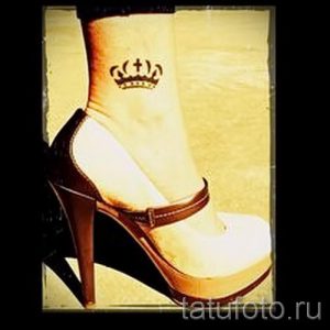 Фото тату: маленькая корона с крестом, выполненная в коричневых тонах, на женской лодыжке. Изящный рисунок татуировки для вдохновения.
