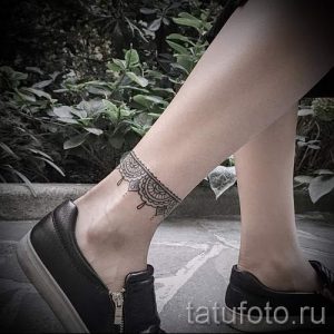 Фото тату: тонкая татуировка, имитирующая кружевной браслет, обвивает лодыжку, выглядит нежно и элегантно.
