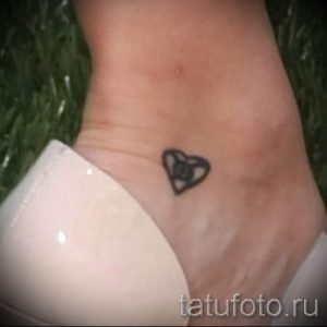 Фото тату маленького сердца на лодыжке. Черно-белый рисунок татуировки в минималистичном стиле.