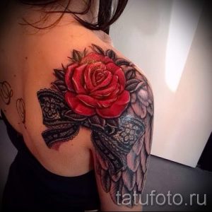 Фото тату: большая красная роза с черным кружевом, расположенная на плече девушки. Реалистичный рисунок татуировки.