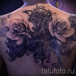 Фото татуировки на спине с изображением белых роз и черного кружева, дополненной бабочками. Идеально для женственного и изящного образа.
