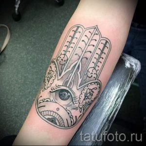 Фото тату Хамса на предплечье. Черно-белый рисунок с детальным глазом и сложными узорами, выполненный в графическом стиле.