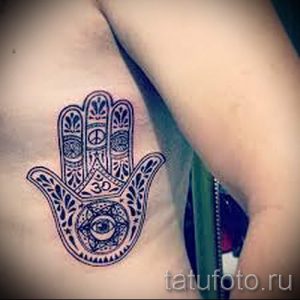 Фото тату Хамсы на груди. Черно-белый рисунок татуировки с изображением символов мира, таких как знак «мир» и символ «Ом».