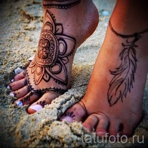 Фото тату хной: сложный восточный узор, украшающий верхнюю часть стопы, дополнен изображением пера. Изысканный и привлекательный дизайн.