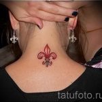 Фото тату на шее: маленькая красная лилия (флёр-де-лис). Простой и элегантный рисунок татуировки.