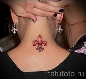Фото тату на шее: маленькая красная лилия (флёр-де-лис). Простой и элегантный рисунок татуировки.