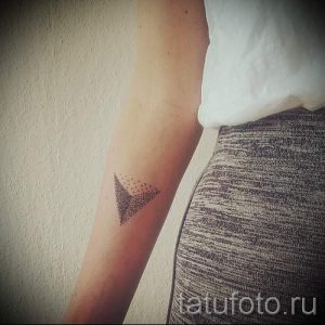 Фото тату на руке в виде треугольника, выполненного точками, минималистичный дизайн.