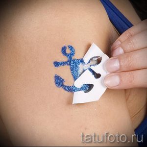 Фото тату: синий блестящий якорь на коже, процесс удаления защитной пленки. Идеи для временных татуировок и глиттер-тату.