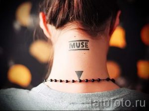 Фото татуировки на затылке: черная надпись 'MUSE' в прямоугольной рамке и маленький треугольник под ней. Минималистичный стиль.