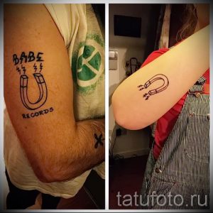 Фото тату подковы с надписью "BABE RECORDS" и оранжевыми молниями на руке. Стильный рисунок татуировки в стиле олдскул с использованием черных контуров.
