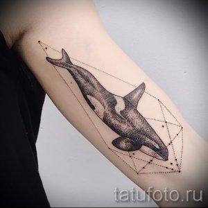 Фото тату косатки в стиле геометрия на предплечье. Черно-белый рисунок с тонкими линиями и геометрическими фигурами вокруг животного.
