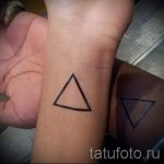 Фотография парных татуировок на запястьях: два черных треугольника, один с заполнением. Стиль - минимализм, геометрия.