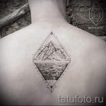Фото тату на спине: геометрический ромб, внутри которого изображены горы и волны. Черно-белый рисунок татуировки в стиле минимализм.