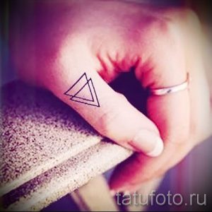 Фото тату: простой контурный треугольник, нарисованный на пальце руки. Минималистичный дизайн.