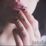 Фото тату: несколько маленьких татуировок на пальцах руки, включая треугольники и символ Анкх. Выполнено в черном цвете.