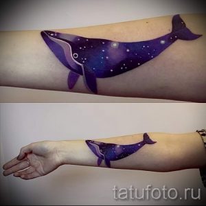 Фото тату: кит, выполненный в виде галактики с звездами и туманностями, на руке.