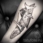 Фото тату кита, выполненного в графичном стиле с использованием геометрических фигур и точечной техники. Черно-белый рисунок татуировки на предплечье.