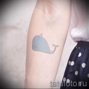 Фото тату маленького голубого кита на предплечье. Простой и милый рисунок татуировки, выполненный в минималистичном стиле.