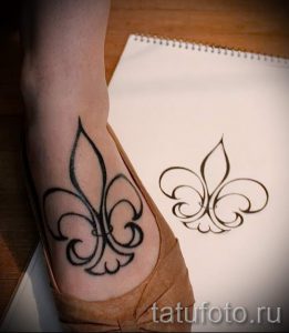 Фото тату Fleur-de-lis на запястье. Простой и элегантный рисунок татуировки в черном цвете, выполненный в стиле минимализм.
