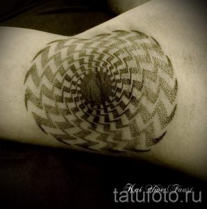 Фотография черно-белой татуировки на руке, выполненной в точечном стиле, изображающей спираль, создающую эффект гипноза.