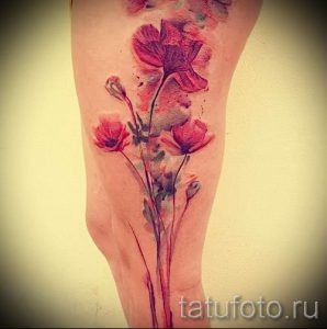 Фотография акварельной татуировки с изображением нескольких маков и стеблей на ноге. Красные, розовые и серые оттенки, изящные линии.