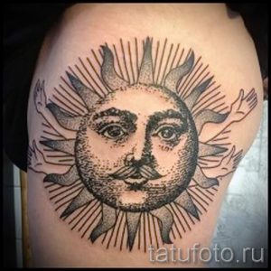Фото тату на предплечье: изображение солнца с человеческим лицом и расходящимися лучами, выполненное в стиле традишнл с использованием черных и серых оттенков.