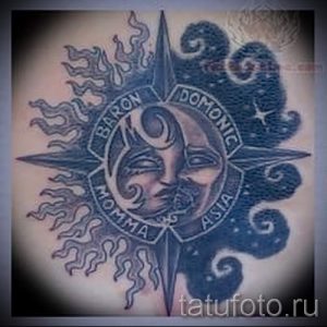 Фото тату на плече: стилизованная роза ветров с изображением луны и солнца, выполненная в черно-серых тонах с надписью.