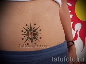 Фото тату: коричневое солнце с точками, расположенное вокруг пупка на животе. Татуировка в этническом стиле, символизирующая тепло и жизненную энергию.