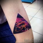 Фото татуировки на плече: треугольник с изображением египетского глаза Ра на фоне космического неба. Яркие цвета, акварельный стиль.