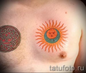 Фотография татуировки на груди, изображающей солнце и луну с человеческими лицами. Яркий и необычный рисунок в стиле олдскул.
