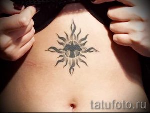 Фото тату солнца на животе. Черно-серый рисунок татуировки в стиле blackwork с геометрическими узорами.