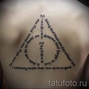 Фото тату на спине: треугольник с символикой Даров Смерти и цитатой из Гарри Поттера. Черный цвет.