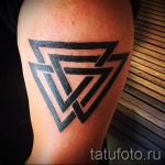 Фото тату на плече: сложная геометрическая композиция из нескольких черных треугольников разного размера. Стильный дизайн.