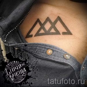 Фото тату на груди мужчины: три черных треугольника, расположенных горизонтально. Минималистичный дизайн.