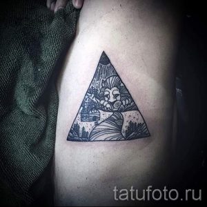 Фото тату: треугольник с изображением льва внутри, расположенный на боку. Стильный рисунок татуировки в черно-белом стиле с детальной проработкой.