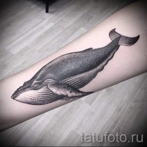 Фото графической татуировки кита на предплечье. Четкие линии и точечная техника создают стильный и современный рисунок.