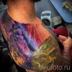 Фото тату космического пейзажа с изображением галактики, гор и молний. Яркий и детализированный рисунок татуировки.