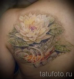 Фото тату реалистичного лотоса и карпа на плече. Детализированный рисунок с использованием ярких цветов и теней.