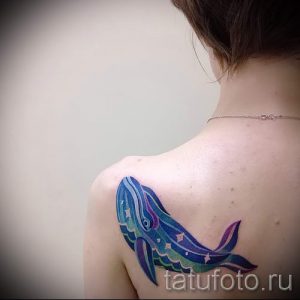 Фото тату: красочная акварельная татуировка кита на плече, выполненная в ярких синих и фиолетовых тонах. Оригинальный и запоминающийся дизайн.