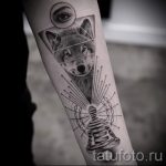 Фото тату на предплечье: реалистичное изображение головы волка в треугольнике с точками и линией ДНК.