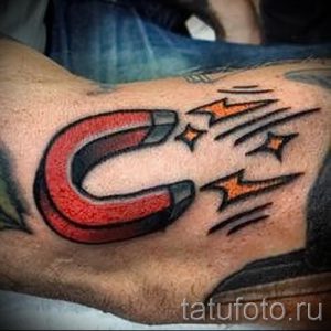 Фото тату подковы с оранжевыми молниями на руке. Традиционный рисунок татуировки в стиле олдскул с четкими контурами и яркими цветами.